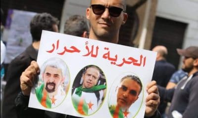 © DR | Khaled Drareni portant une pancarte en soutien à Samir Belarbi, Slimane Hamitouche et Toufik Hassani