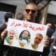 © DR | Khaled Drareni portant une pancarte en soutien à Samir Belarbi, Slimane Hamitouche et Toufik Hassani